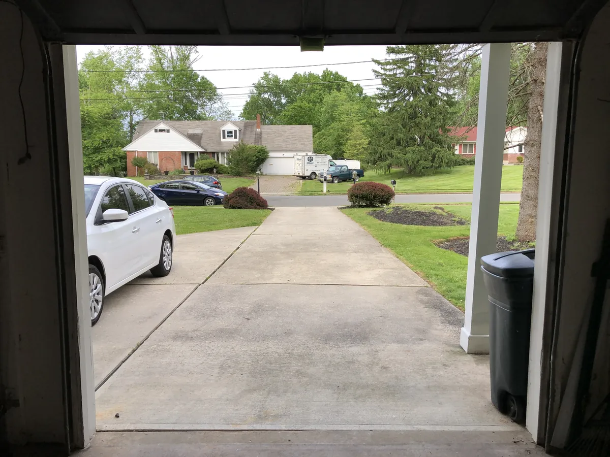 View from inside a garage looking out at a driveway and suburban street