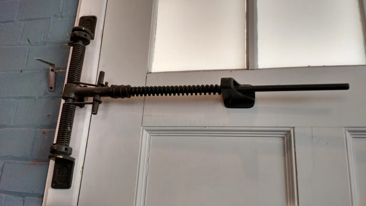 Close-up of a garage door spring and hinge hardware on a white door